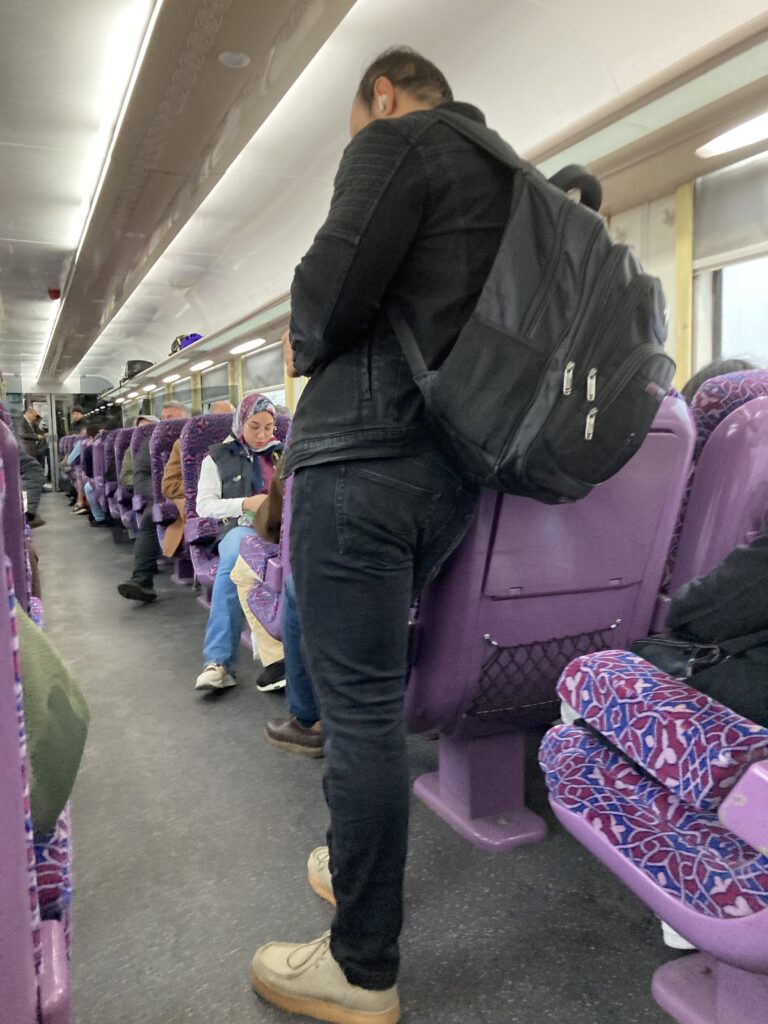 Scene in a first class car on the ONCF train from Meknes to Marrakech. Passengers from second class cars sometimes stand or sit in the first class car despite not having a proper ticket. It is somewhat annoying to seated passengers that they invariably bump into during the ride.