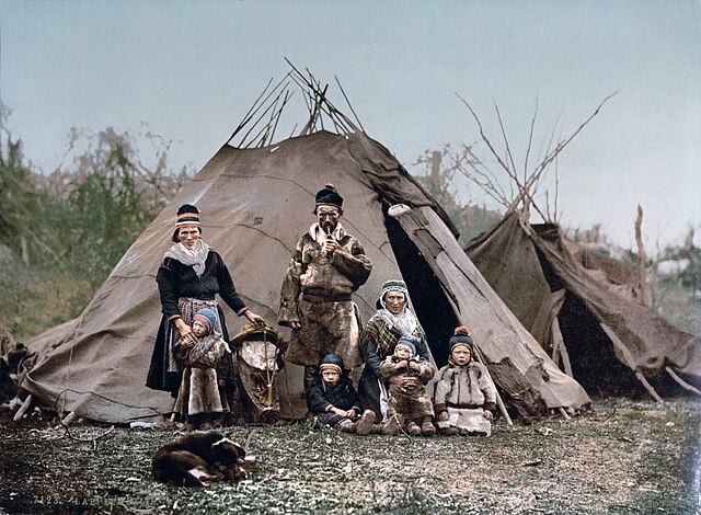 A family of Sámi people in front of their lavvu, with a dog in the foreground. Norway c. 1900